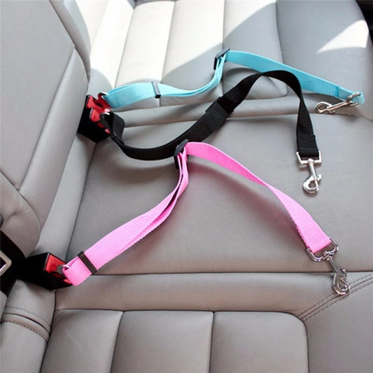 Three dog leashes attached to a car seat with a pink leash on top and a black leash on the bottom.