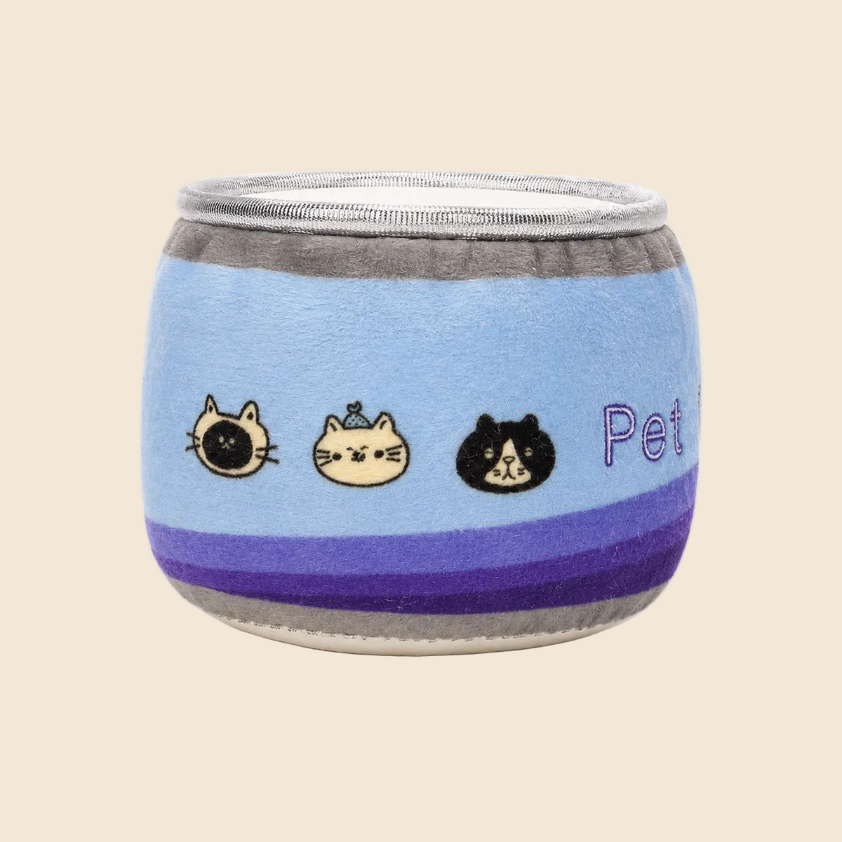 A plush pet toy designed like a small cylindrical container, featuring a light blue body with purple stripes, gray top and bottom trim, embroidered cat faces, and the partial text 'Pet' on the side, set against a plain off-white background.