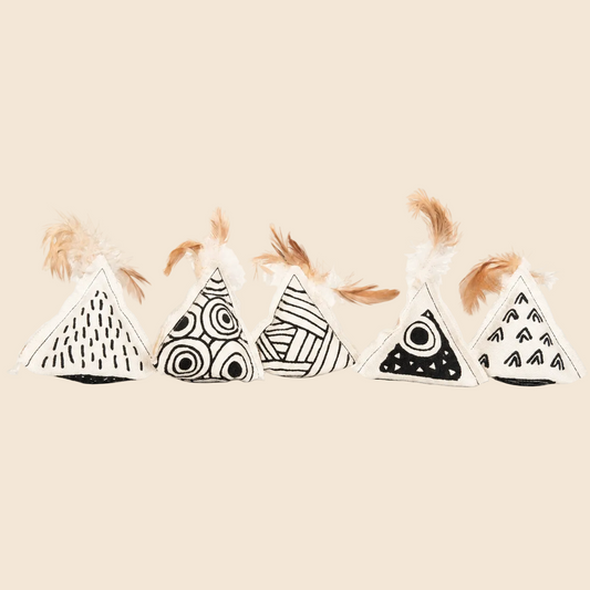 Four small triangular fabric toys with black-and-white geometric patterns and light brown feathers on top, arranged in a row on a plain off-white background.