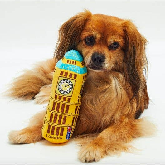 Dog holding a Big Ben toy on a white background