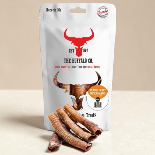 A stand-up pouch of The Buffalo Co. dog treats on a light beige surface against a beige background.