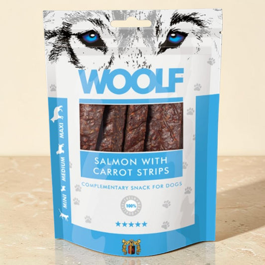 A stand-up pouch of WOOLF dog treats, specifically Salmon with Carrot Strips, featuring a graphic of a wolf's face at the top and a clear window showing the brown treats inside. The packaging is white and light blue.