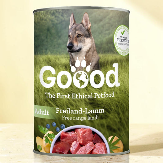 A can of Good brand adult free range lamb dog food, featuring a label with a wolf in a green field and a bowl of raw lamb meat, set against a light beige background.