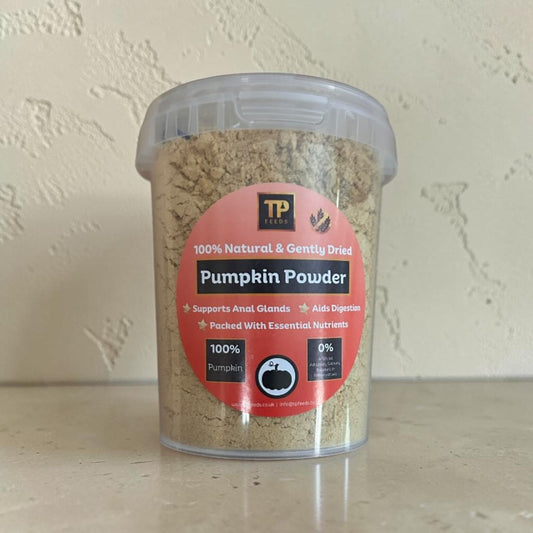 A clear plastic tub of TP Petals Pumpkin Powder with a red and black label, set on a beige surface against a textured beige wall.