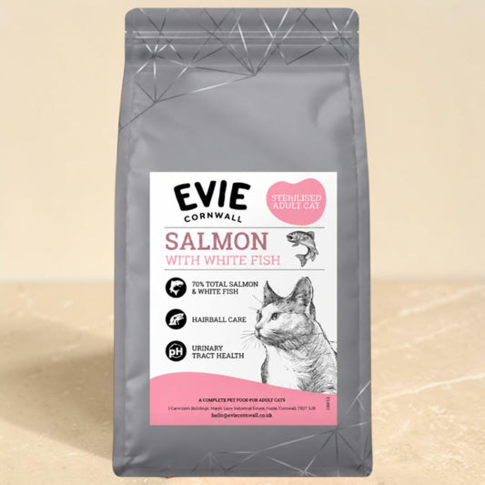A bag of Evie Cornwall Salmon with White Fish dry cat food, featuring a gray pouch with a white and pink label, set against a light beige background.