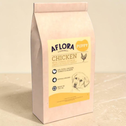 A bag of Aflora Cornwall Puppy Chicken wet food, featuring a pale pinkish-beige bag with a cream and yellow label, set against a neutral beige background.