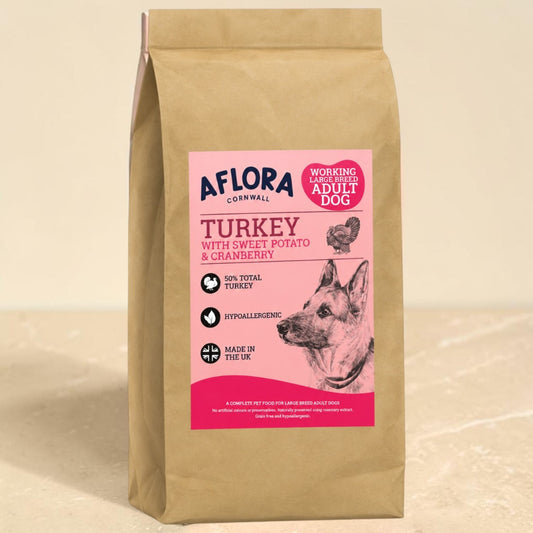 A bag of Aflora Cornwall Turkey with Sweet Potato & Cranberry dog food, in a brown kraft paper bag with a pink and white label, set against a neutral beige background.