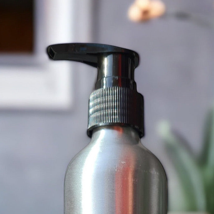 Silver spray bottle with black pump head on a blurred background