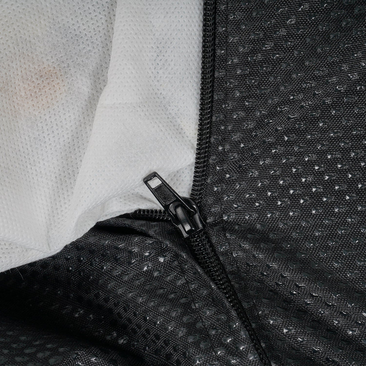 Close-up of a textured black garment with a zipper on a light background