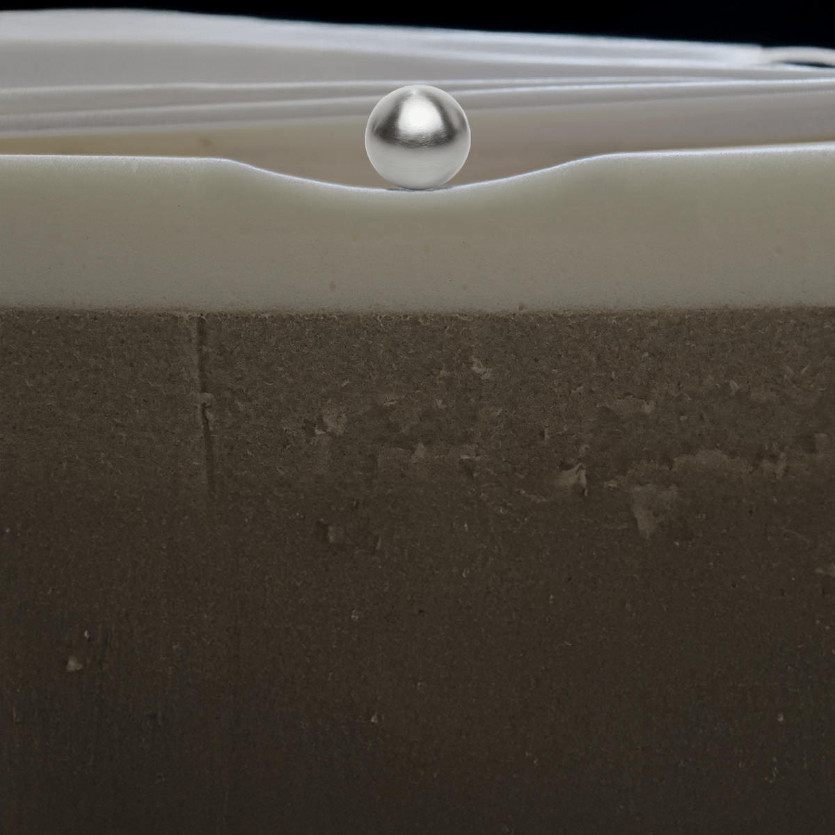 Close-up of a textured surface with a metallic sphere on top against a black background